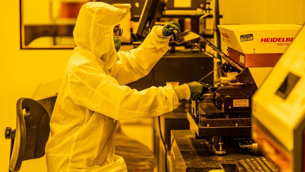 A gowned NRC researcher making a photomask using the mask writer instrument in the cleanroom of the CRAFT Device Foundry at the University of Toronto.